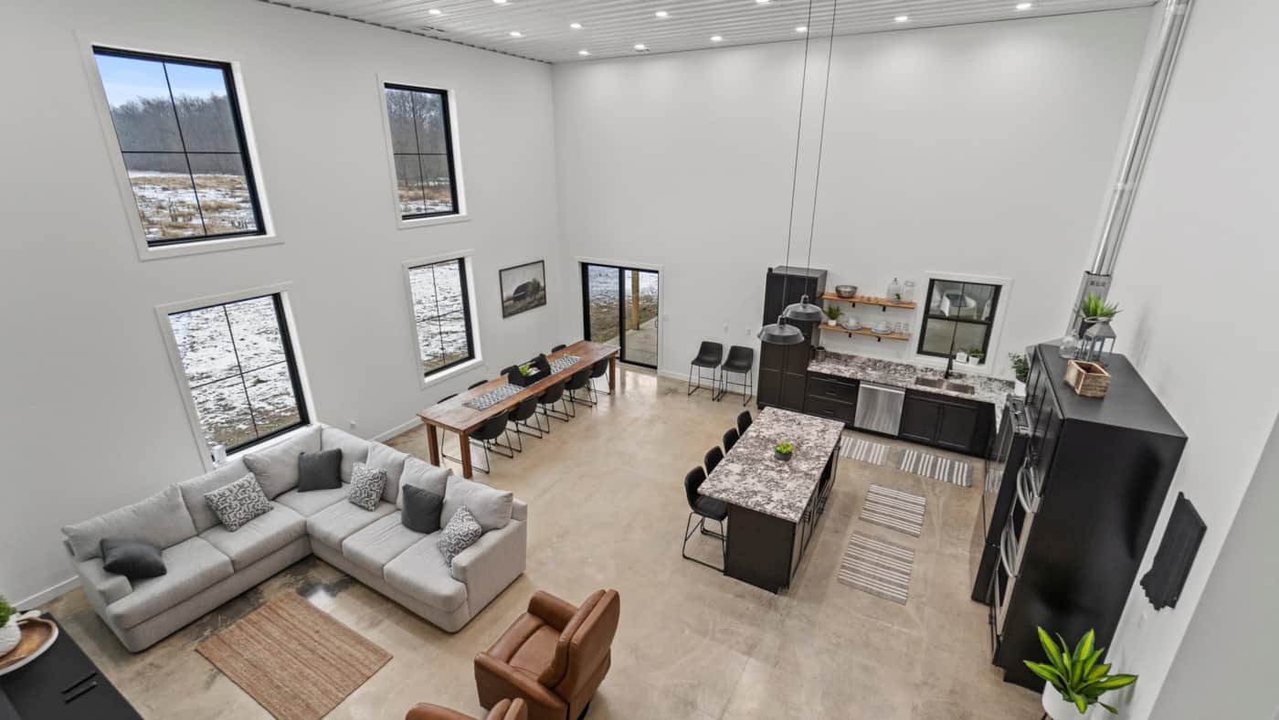 Open great room with sectional sofa, long dining table and kitchen island